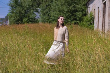 Genç bir kadın yaz sıcağının ortasında bir tarlada kuru otların arasında.