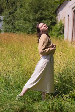 Genç bir kadın yaz sıcağının ortasında bir tarlada kuru otların arasında.