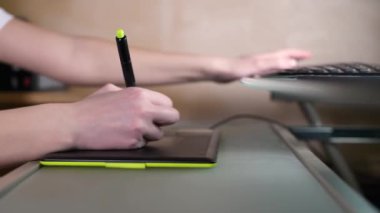 Kamera hareket ediyor ve grafik tabletinde bir kızın elinin yakın çekimini gösteriyor..