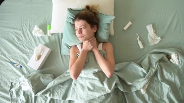 Een ziek uitziende jonge vrouw lijdt en blaast haar neus in een servet — Stockvideo