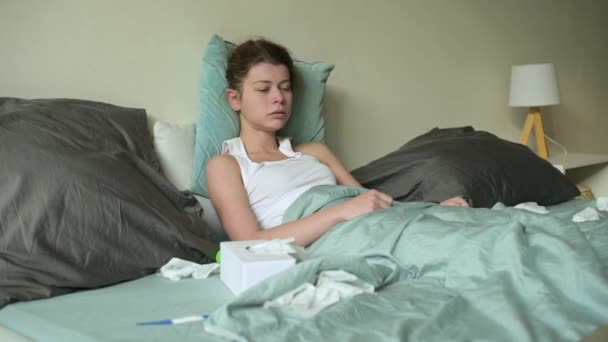 Frau nimmt Medikamente im Bett und pustet Nase in Einwegtaschentuch — Stockvideo