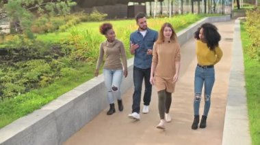 Parkta yürüyen ve sohbet eden dört kişilik arkadaş grubu.