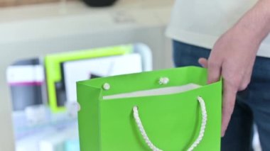 Bir adam bir mağazaya kağıt bir torba içinde mal koyar, yakın plan. Mağazadan satın alma