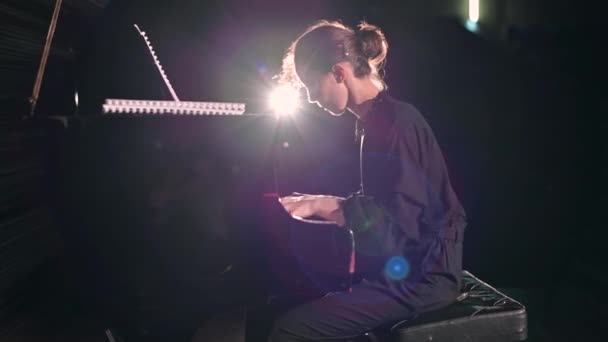 若い女性がステージ上のスポットライトで精力的にピアノを演奏する — ストック動画