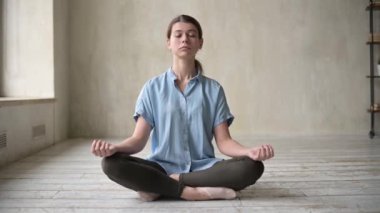 Genç bir kadın boş bir dairede meditasyon yapıyor. Ahenk aranıyor