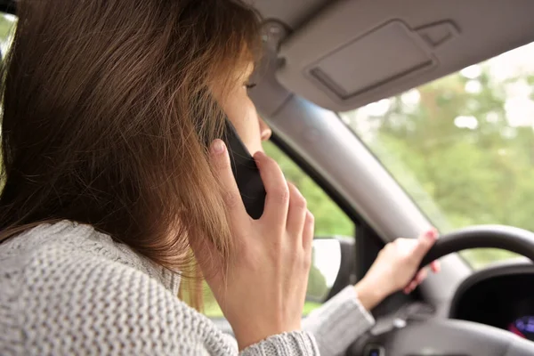 The woman answers the phone while driving. Driver creates danger by talking on the phone while driving