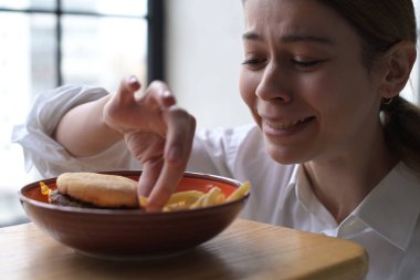 Bir tabak fast food, karşı koyamayan ve tabaktan patates yiyen genç bir kadını baştan çıkarır.