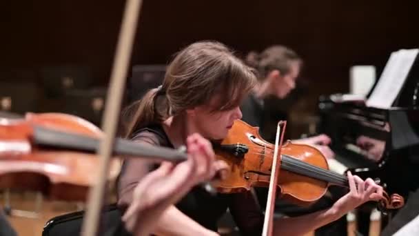 Focus op een jonge vrouw die viool speelt met een strijkkwartet en vleugel — Stockvideo
