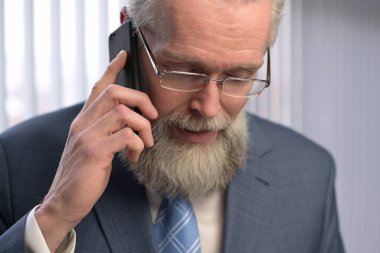 Yetişkin, beyaz saçlı, saygıdeğer bir adam telefonda iş konuşur. Patron telefonla arıyor ve raporlar hakkında konuşuyor. Gazetelere bakıyor. Telefonda iş görüşmesi.