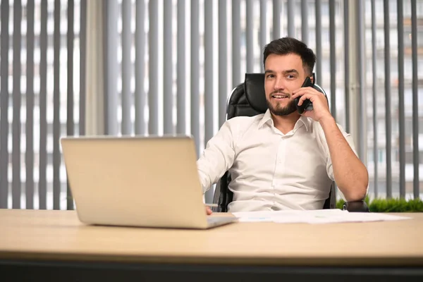 Young office director talking on phone with colleagues and partners remotely