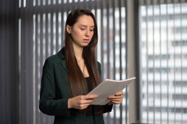 Genç bayan evrakları inceliyor, ofiste onlara bakıyor. Kadın ofis çalışanı