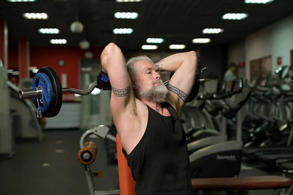 Gray Haired Adult Man Doing French Press Barbell While Sitting Stock Photo