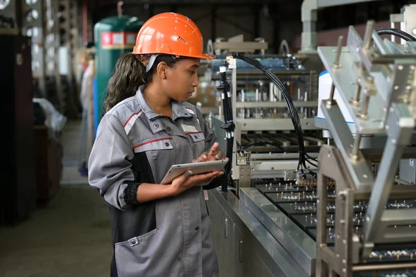 A young black manufacturing worker controls an assembly line in a factory