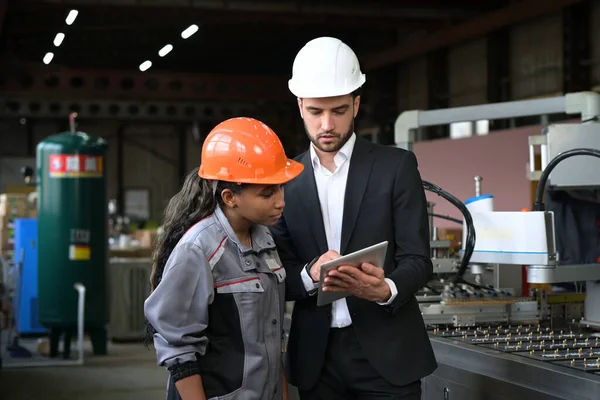 Een jonge leider van de transportband bespreekt werkprocessen met een vrouwelijke werknemer Stockfoto