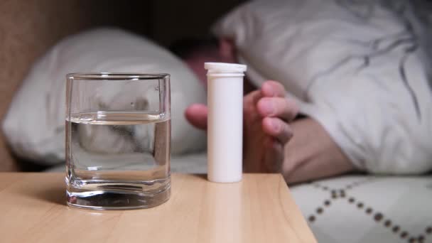 Gros plan d'un verre dans lequel un homme jette une pilule soluble — Video