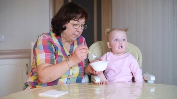 Бабуся годує онуку ложкою. Дівчина їсть — стокове відео