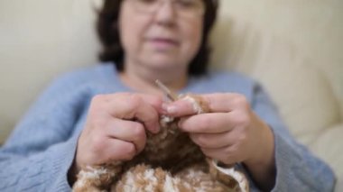 Eşarp ören bir kadının elleri, arka planda yüzü dağılmış bir şekilde.