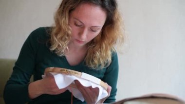 Kız resme bakıyor ve deseni nakışlıyor.