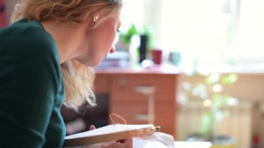 Tuvale iplik desenini sessizce nakışlayan genç bir kadının yan görüntüsü