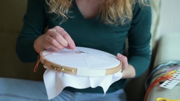 Close-up van de blanco in de handen van een meisje dat borduurt in haar vrije tijd — Stockvideo