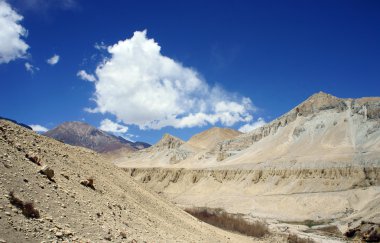 Yüksek dağların üzerinden mavi gökyüzünde beyaz bulutlar