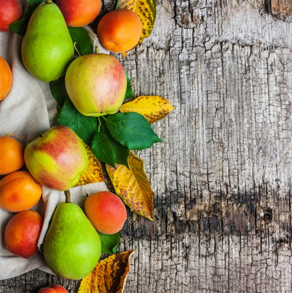 Äpplen, päron och aprikoser på en trä bakgrund Stockbild
