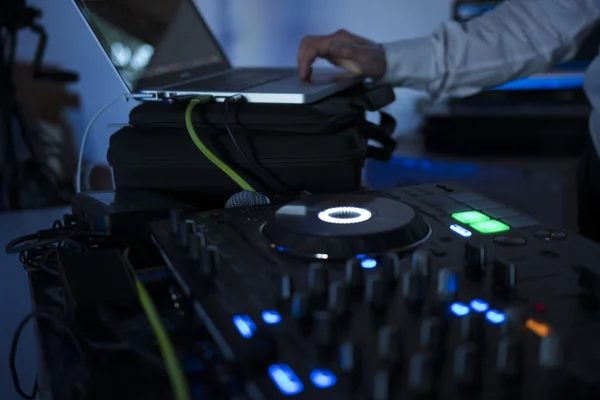 Dj mixes the track in nightclub at party with dancing people on blur background — Stock Photo, Image