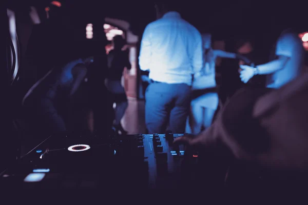 Dj mescola il brano in discoteca alla festa con persone che ballano su sfondo sfocato — Foto Stock