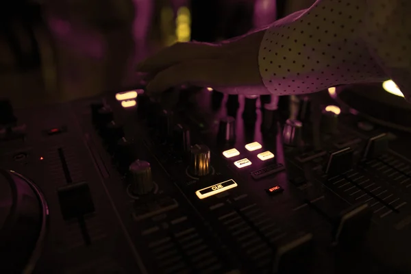 DJ blandar spår i nattklubb på fest med dansande människor på oskärpa bakgrund — Stockfoto
