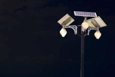 Gece gökyüzü ve beyaz bulutlu güneş paneli aydınlatma direği. Yenilenebilir enerji kavramı.