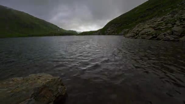 El lapso de tiempo en una orilla del lago con la roca en primer plano y el rápido cambio del tiempo — Vídeos de Stock