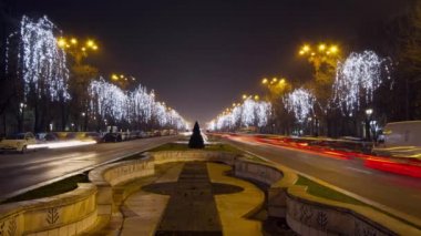 Gece trafik sıkışıklığı Unirii Bulvarı'nda. Ağaçlar ışıklar perde ile dekore edilmiştir. Zaman atlamalı pan vurdu.