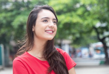 Kırmızı gömlekli açık bir parkta güzel kadın