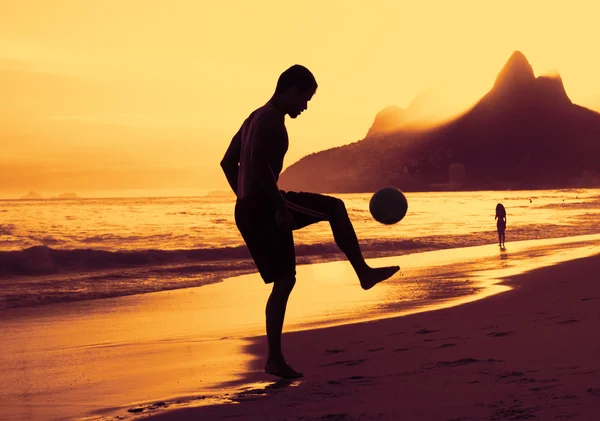 Kerl spielt Fußball am Strand von Rio bei Sonnenuntergang — Stockfoto