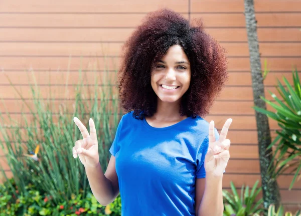 Mujer latina con camisa azul mostrando signo de victoria — Foto de Stock