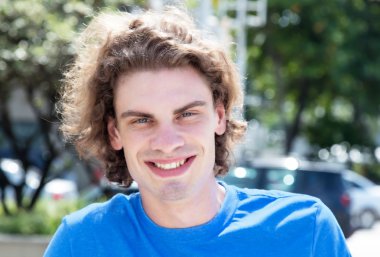 Şehirde uzun saçlı beyaz adam gülüyor