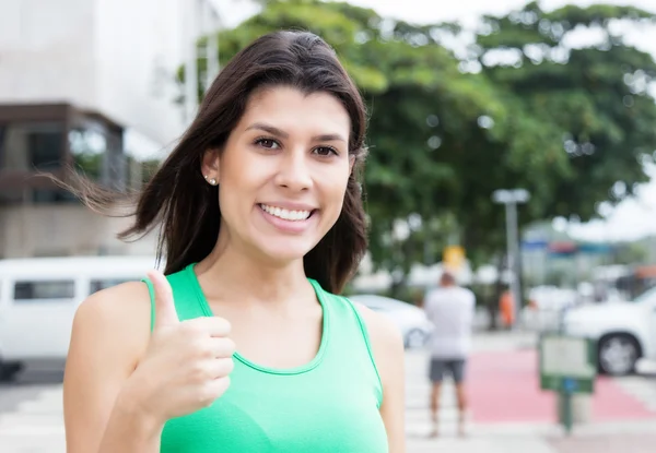 Kvinna i en grön skjorta i staden visar tummen — Stockfoto