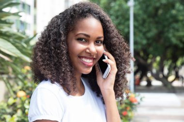 Telefon bir parkta, kıvırcık saçlı güzel latin kadın