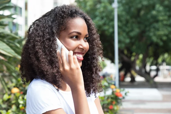 Rindo mulher latina com cabelo encaracolado no telefone em um parque — Fotografia de Stock