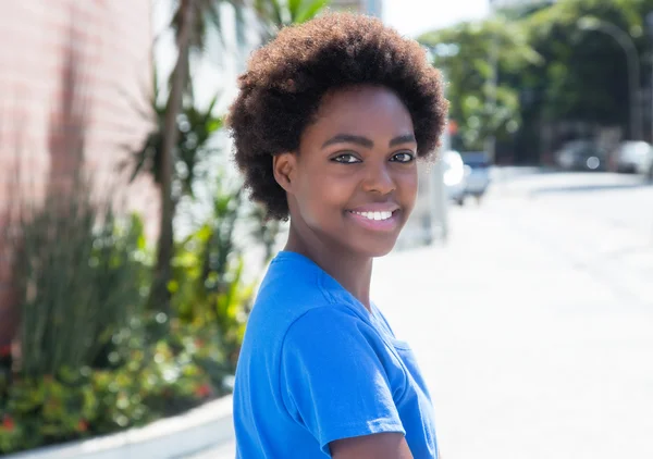 Mulher africana bonita em uma camisa azul ao ar livre na cidade — Fotografia de Stock