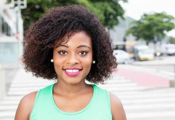 Mulher rindo da África em uma camisa verde na cidade — Fotografia de Stock