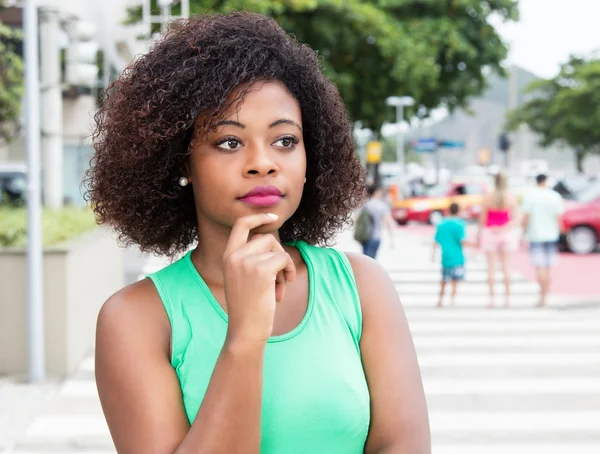 Pensant femme de l'Afrique dans une chemise verte en ville — Photo