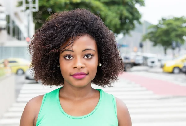Mujer sonriente de África con una camisa verde en la ciudad —  Fotos de Stock