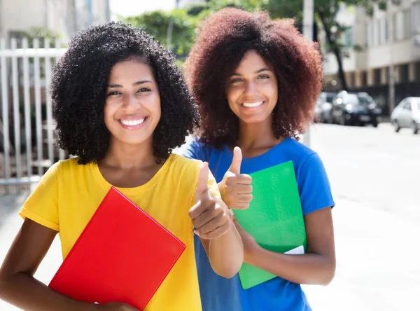 Twee Latijnse vrouwelijke studenten tonen duim — Stockfoto