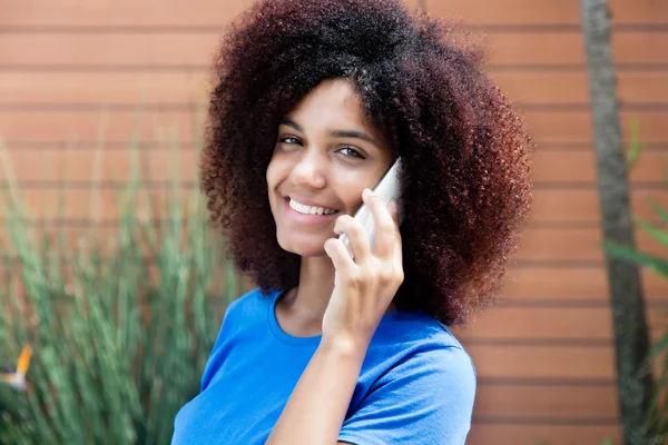 Latijnse vrouw in blauw shirt met telefoon — Stockfoto