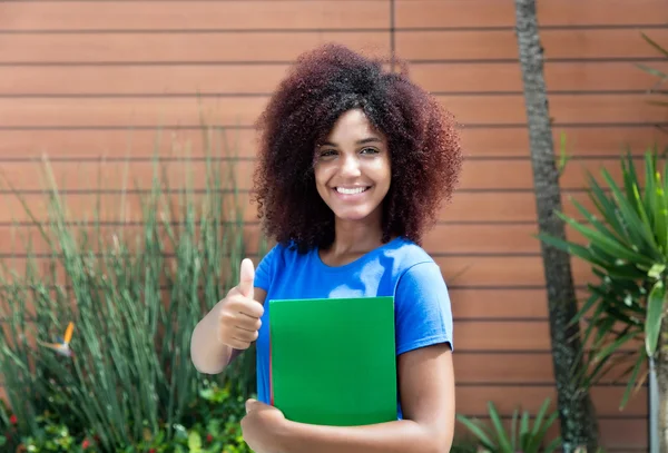 Latinska kvinnlig student i blå skjorta visar tummen — Stockfoto