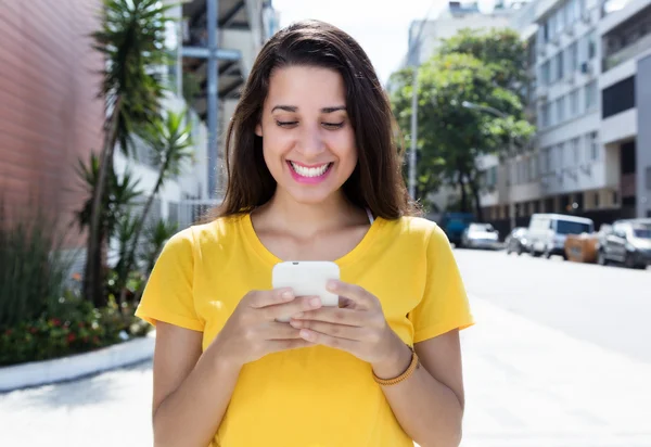 Белая женщина в жёлтой рубашке отправляет сообщение с телефоном в Си — стоковое фото