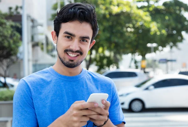 Feliz tipo hispano enviando un mensaje por teléfono —  Fotos de Stock