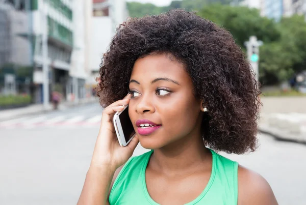 Mulher de África em uma camisa verde no telefone na cidade — Fotografia de Stock