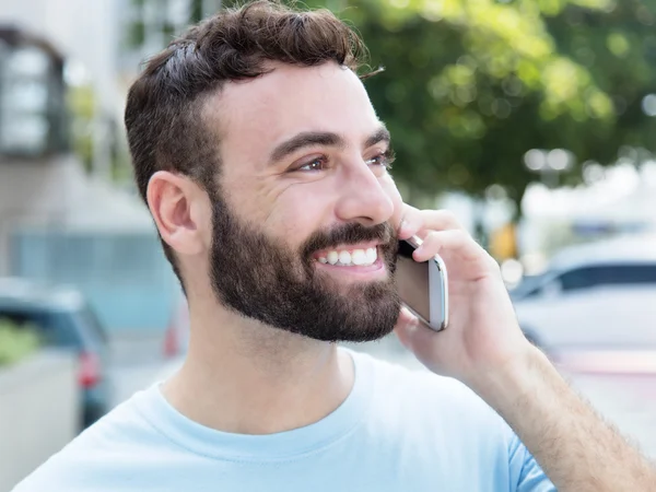 Caucasian man with beard at phone outdoor in city Royalty Free Stock Images